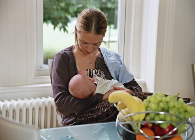 Mum sat at a table breastfeeding
