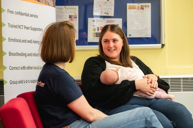 Peer supporter talking to Mum while feeding her baby